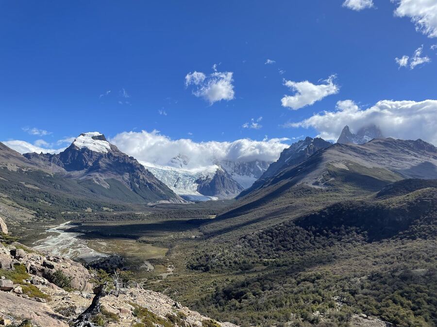 A glacier pouring between dark peaks under a blue sky