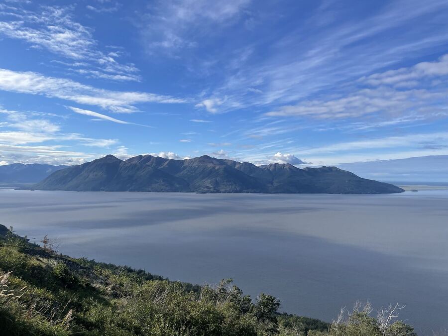 A calm fjord below a long dark ridge, thin high clouds above