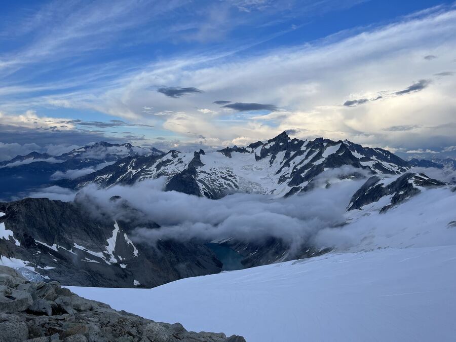 A sea of cloud filling a valley below snowy peaks