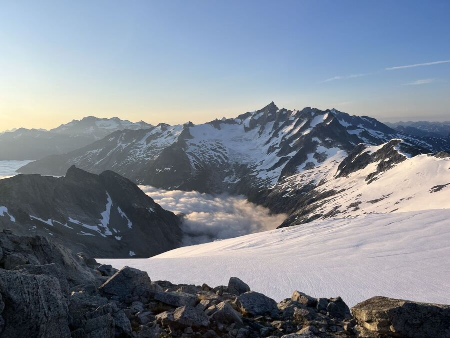 Early light over snowfields and jagged peaks, cloud in the valleys