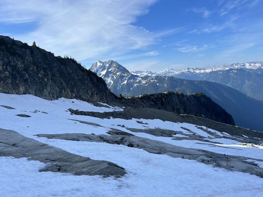 A snow slope leading to dark ridges and a distant peak